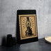 a black frame with a vintage-style illustration of a lantern on it, placed on a dark surface next to some black camera lenses.