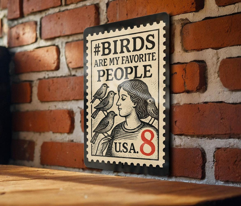 A metal sign with a stamp-like design hangs on a brick wall, featuring a woman with birds perched on her shoulders.