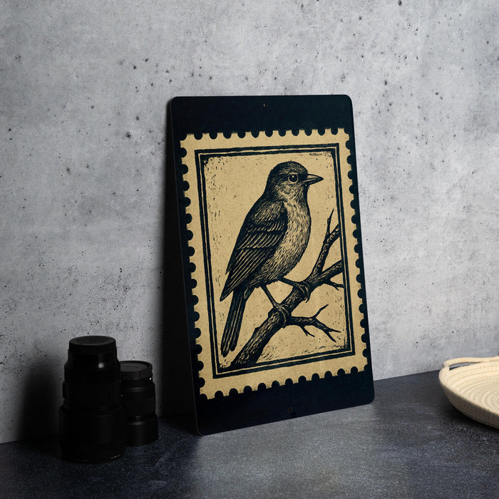 a framed illustration of a bird perched on a branch, placed on a table next to some black camera lenses.