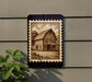 a wooden barn with a porch, depicted in a stamp-like design on a wall.