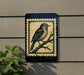 a black and white bird perched on a branch, depicted on a sign mounted on a wall.