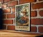 A metal stamp depicting a woman holding a basket of plums, with the text "PLUM HARVEST" printed on it. The stamp is mounted on a brick wall.