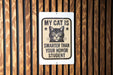 a sign with a cat's face and the text "MY CAT IS SMARTER THAN YOUR Honor STUDENT" on a wooden background.