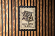 A sign that reads "QUILTING FRAME" is displayed against a wooden background.