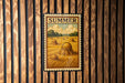 A framed illustration of a field with hay bales is displayed on a wooden wall.