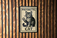 A metal sign with a cat illustration and the text "POLYDACTYL CAT" is displayed on a wooden wall.