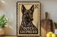 A metal sign featuring a black and white illustration of a Dutch Shepherd dog, with the text "DUTCH SHEPHERD" printed on it. The sign is placed on a shelf next to a wooden cutting board and a potted plant.