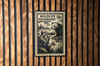 A wildlife photography stamp is displayed on a wooden wall, featuring a person photographing a bear.