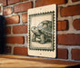 A sign featuring a detailed illustration of a turtle is mounted on a brick wall.