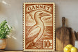 a wooden sign with a bird illustration, placed on a wooden surface next to a potted plant and some kitchen utensils.