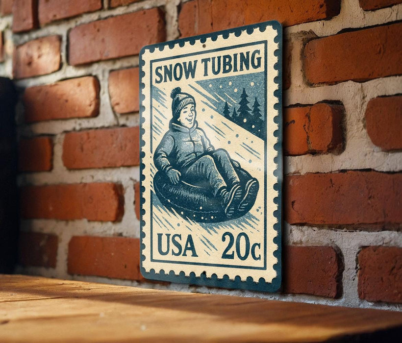 A vintage-style postage stamp depicting a person riding a snow tube, mounted on a brick wall.