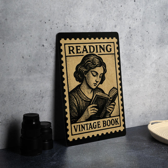 A vintage-style metal sign with the text "Reading Vintage Book" and an illustration of a woman reading a book.