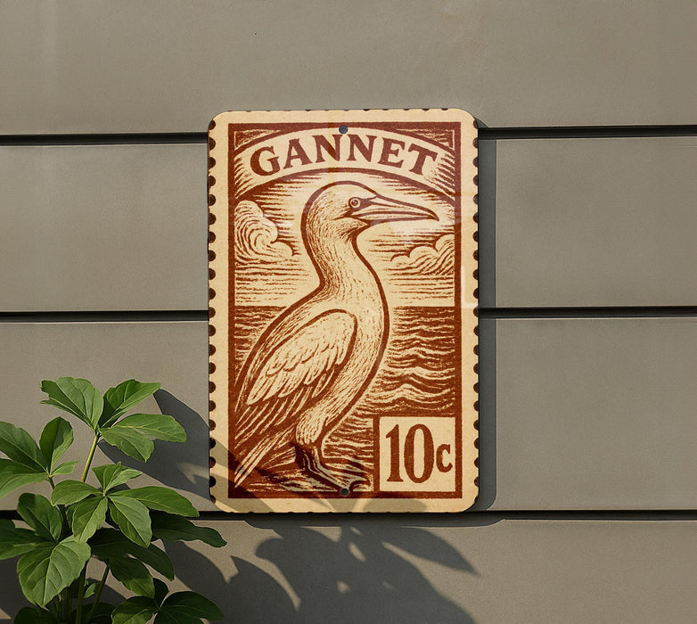 A wooden sign with a bird illustration and the word "GANNET" printed on it, mounted on a wall.