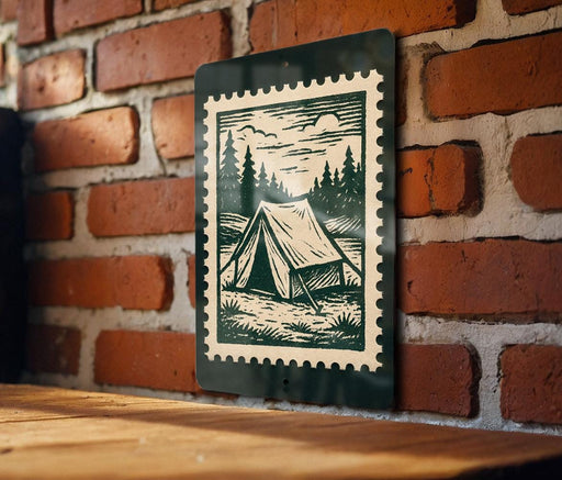A green and white stamp-like sign is mounted on a brick wall, depicting a tent in a wooded area.
