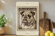 a framed illustration of an English Bulldog on a shelf, with a wooden cutting board and a potted plant nearby.