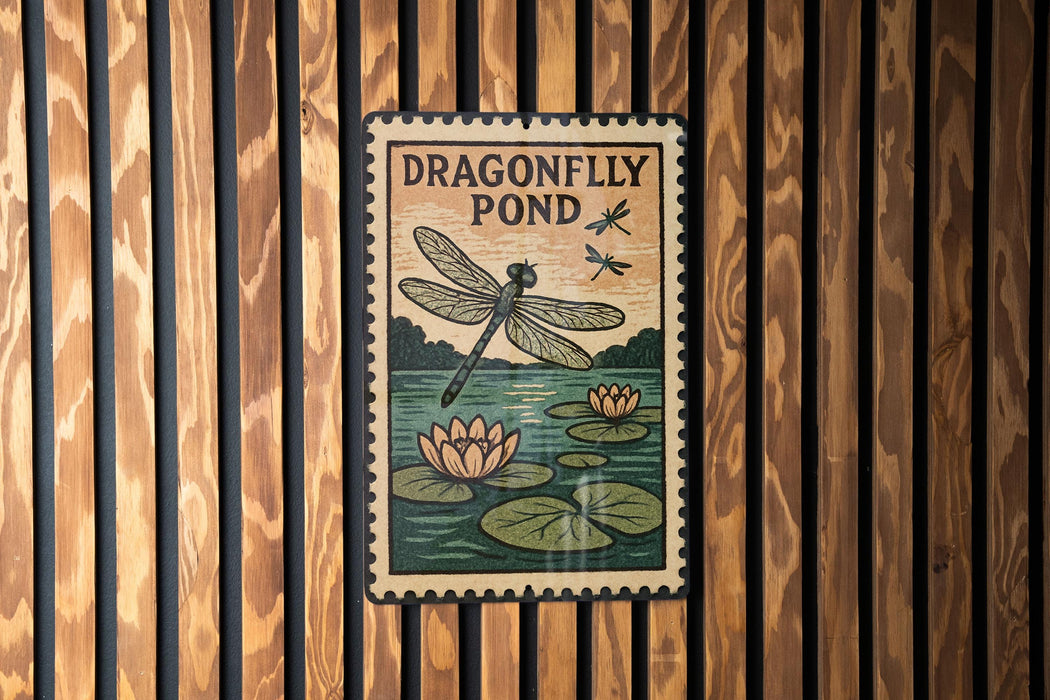 A sign for a dragonfly pond hangs on a wooden wall, featuring a dragonfly and lily pads.