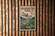 A sign for a dragonfly pond hangs on a wooden wall, featuring a dragonfly and lily pads.