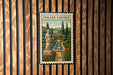 a vintage-style metal sign with a painting of a garden, mounted on a wooden wall.