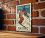 A vintage-style 20c postage stamp featuring a skier on a mountain slope, mounted on a brick wall.