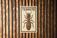 A sign with the word "TERMITE" and an illustration of a termite on a wooden background.