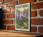 A vintage postage stamp featuring a lush garden scene with purple flowers, mounted on a brick wall.