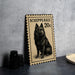 a black and white illustration of a dog on a postage stamp, placed on a table next to some black camera lenses.