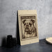 a sign with a bulldog illustration on it, placed on a table next to some black camera lenses.