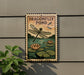 A sign for a pond with a dragonfly, featuring a dragonfly and water lilies, mounted on a wall next to a plant.