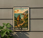 A metal sign with a vintage-style illustration of a hiker on a coastal trail, surrounded by lush greenery and a scenic landscape.