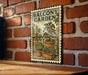 A framed illustration of a balcony garden is displayed on a brick wall, featuring potted plants and a tree.