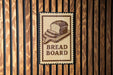 A sign with the word "BREAD BOARD" is displayed on a wooden wall.