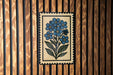 a decorative tile with a floral design, mounted on a wooden wall.