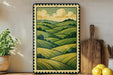 a framed painting of a countryside landscape with rolling hills and trees, displayed on a shelf next to a wooden cutting board and a potted plant.