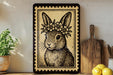 A framed illustration of a rabbit wearing a flower crown is displayed on a shelf, accompanied by a wooden cutting board and a potted plant.