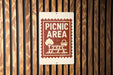 A sign indicating a picnic area is mounted on a wooden wall.