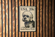 A black and white postage stamp featuring a Dandie Dimmont Terrier dog.
