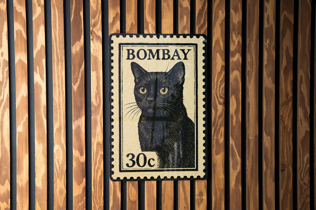 A black cat stamp with the text "BOMBAY 30c" is displayed on a wooden wall.