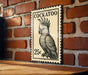 A vintage-style postage stamp featuring a detailed illustration of a cockatoo, mounted on a brick wall.