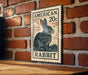 A wooden table with a vintage-style sign featuring an illustration of a rabbit on a brick wall.