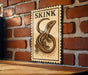 A wooden table with a brick wall in the background, and a framed illustration of a lizard on the wall.
