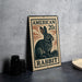 A metal sign featuring an illustration of a rabbit on a postage stamp, placed on a table next to some black camera lenses.