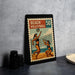 A framed vintage stamp depicting a beach volleyball game, with two players in action.