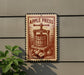 a vintage-style metal sign with an illustration of an apple press, mounted on a wall.
