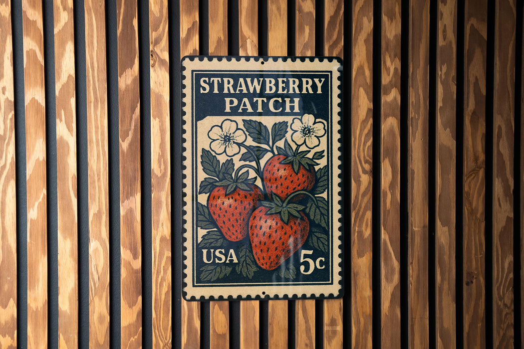 A vintage-style postage stamp featuring a strawberry patch, mounted on a wooden wall.