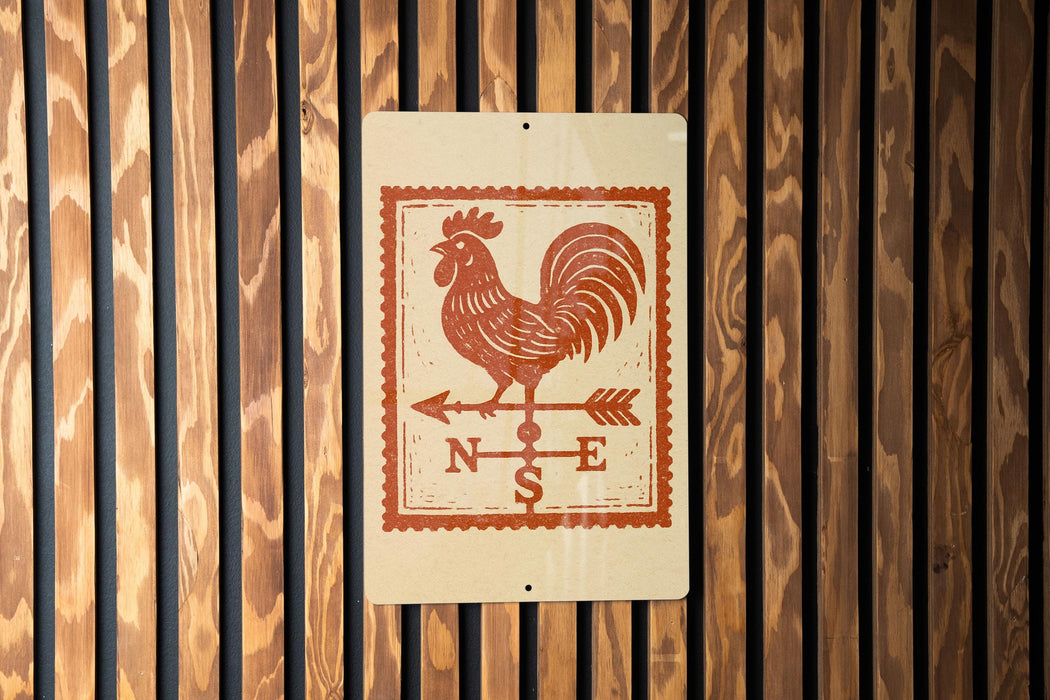 a sign with a rooster and a weather vane, mounted on a wooden wall.