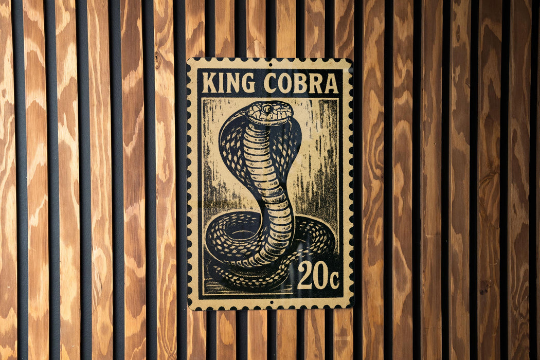 A black and white stamp-like image of a king cobra is displayed on a wooden wall.