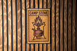 A metal sign with a flame on it is mounted on a wooden wall.