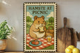 A metal sign with a cartoon hamster sitting on a picnic blanket, holding a sandwich and surrounded by fruits and a basket, with the text "HAMSTE AT PICNIC" displayed.