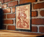 A metal sign with a cartoon illustration of a woman holding a hamster, mounted on a brick wall.