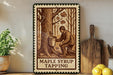 A framed illustration of a person tapping a tree to collect maple syrup, with the text "M maple syrup tapping" below the image.